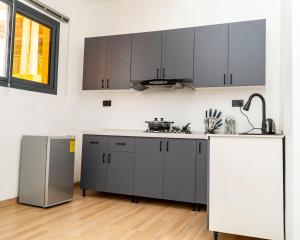 une cuisine avec des armoires grises et un évier dans l'établissement The Milon Apartment, à Kigali