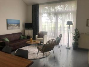 a living room with a couch and a table and chairs at De Wijde Verten in Oostkapelle