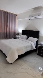 a bedroom with a large white bed with a window at Departamento Sol in Santo Domingo