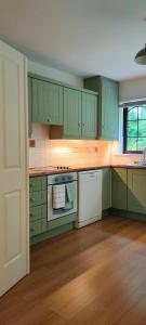 a kitchen with green cabinets and white appliances at Rynn Haven - Enchanting Townhouse Lough Rynn in Mohill