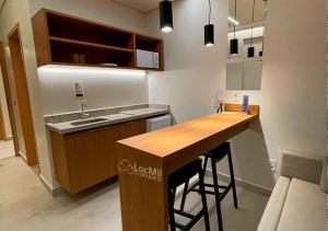 a kitchen with a sink and a bar with stools at Apartamento em Resort - Premium in Salinópolis