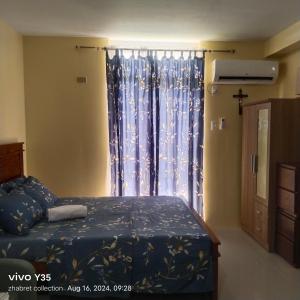 a bedroom with a bed and a large window at Zhabret's Place II in Lapu Lapu City