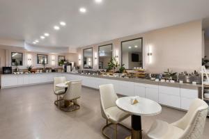 a kitchen with white chairs and tables and a counter at Ramada by Wyndham DFW Airport in Irving
