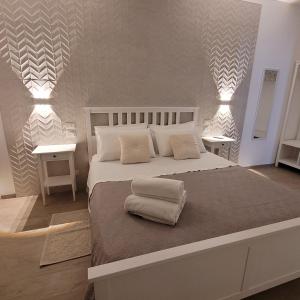 a white bedroom with a large bed with two tables at House Torre Galea 2 in Marina di Gioiosa Ionica