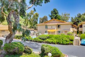a house with a tree in a parking lot at Oceanside Condo with Pool and Hot Tub Access! in Oceanside