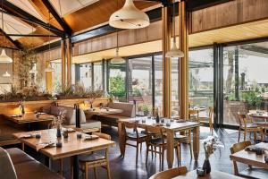 a restaurant with wooden tables and chairs and windows at Stanly Ranch, Auberge Collection in Napa