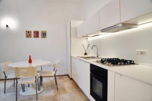 a white kitchen with a small table and a sink at Dormi da noi in Ancona