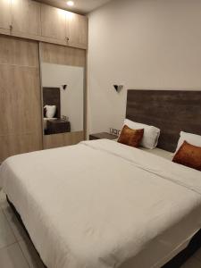 ein großes weißes Bett in einem Schlafzimmer mit einem Spiegel in der Unterkunft Skynest Residences by Lisa's Paradise D in Nairobi + 39 Fotos