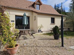 a patio with an umbrella and a picnic table in front of a house at Maison charmante près des jardins de Monet avec jardin clôturé. in Sainte-Geneviève-lès-Gasny
