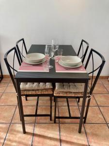 a black table with chairs and plates and wine glasses at EL PATIO De Arguineguìn in Arguineguín