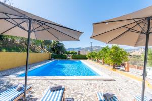 una piscina con due sedie e due ombrelloni di Cortijo el Masegal, Carcabuey, centro de Andalucia a Carcabuey