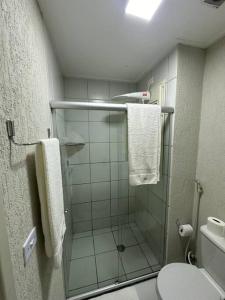 a bathroom with a shower and a toilet and towels at O EDIFÍCIO é de frente ao MAR de Pajuçara NEO 2 Qts 2gar - Adm Nutelss in Maceió