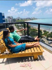 two people sitting on a bench on top of a building at O EDIFÍCIO é de frente ao MAR de Pajuçara NEO 2 Qts 2gar - Adm Nutelss in Maceió +34 photos