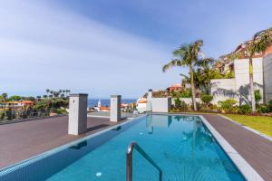a swimming pool on the roof of a building with the ocean in the background at Enchanted Bay in Câmara de Lobos