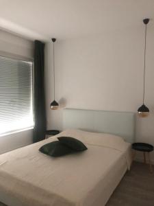 a bedroom with a white bed with two pendant lights at Halal Kuca sa bazenom u Mostaru in Mostar