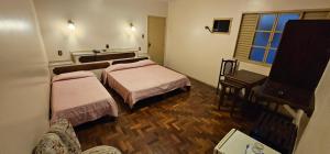 a small room with two beds and a piano at Hotel Colonial in São João del Rei