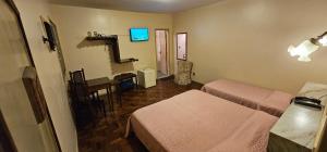 a room with two beds and a table and a television at Hotel Colonial in São João del Rei