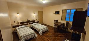 two beds in a room with a piano at Hotel Colonial in São João del Rei