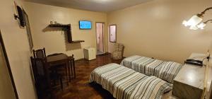 a living room with two beds and a table at Hotel Colonial in São João del Rei