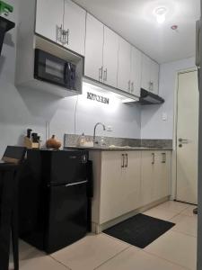 a kitchen with white cabinets and a sink and a microwave at Cool Suites SMDC Tagaytay in Tagaytay +6 photos
