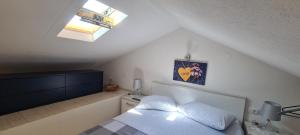 1 dormitorio en el ático con 1 cama y tragaluz en Studio apartman Loreta, en Cres