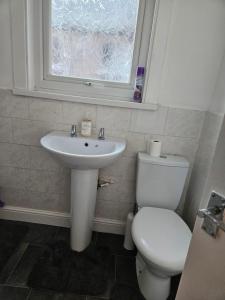 a bathroom with a toilet and a sink and a window at Liverpool Haven, Stylish and Spacious 3-Bedroom Apartment with City Access in Liverpool