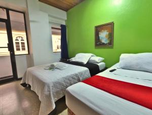 a room with two beds and a green wall at Hotel Alajuela Costa Rica Airport in Alajuela City