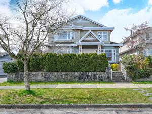 a white house with a stone wall and a tree at 7 Bedrooms in the Heart of Vancouver in Vancouver