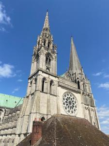 a large cathedral with a clock tower on a blue sky at La Suite - Cathédrale in Chartres