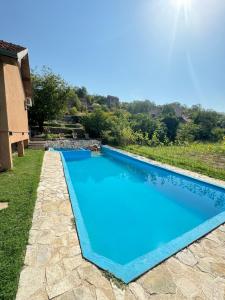 a blue swimming pool in a yard with a house at Casa Madre Kravice Waterfalls in Ljubuški