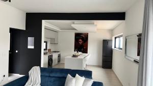 a living room with a blue couch and a kitchen at CasaZina in Tarrafal