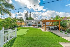 a house with a white fence and a yard with green grass at Tank Pool, Putting Green & 1 Mile To The Beach! in Lantana
