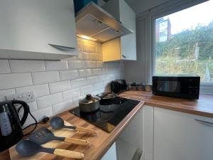 a kitchen with a stove top with wooden spatulas at Luton Airport House, Opposite airport staff parking in Luton