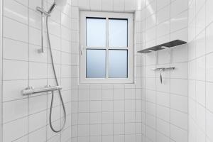 a shower with a window in a white bathroom at Fun Art Holiday Apartment Lots Of Fun For The Whole Family! in Pandrup +14 photos