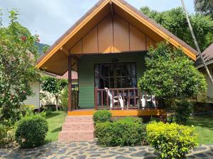 a green house with two white chairs on the porch at Koh Chang Bailan Beach Resort in Ko Chang