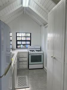 a white kitchen with a stove and a window at Seaspray, St James in Saint James +9 photos