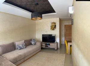 Appartement avec piscine à casa tamaris في دار بوعزة: غرفة معيشة مع أريكة وتلفزيون بشاشة مسطحة