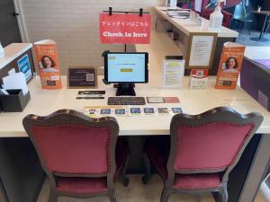 a desk with two chairs and a computer on it at New Normal Hotel in NAMINOUE ニューノーマルホテルイン波の上 in Naha