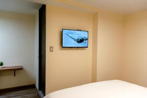 a bedroom with a tv on the wall at Aerosuites & SkyHub in Bogotá