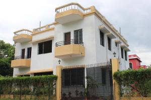 a white house with a black iron gate at Udita (উদিতা) Eco Homestay Santiniketan in Shānti Niketan