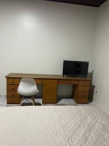 a desk with a television and a chair in a room at Edícula in Porto Velho