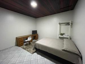 a bedroom with a bed and a desk and a mirror at Edícula in Porto Velho