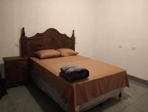 a bed with a wooden headboard and a brown blanket at Valle de Toliman in San Lucas Tolimán