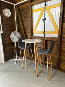 a table and two chairs and a clock on a wall at Un Petit Coin Paisible in Capesterre-Belle-Eau