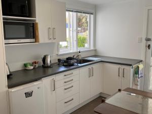 a kitchen with white cabinets and a black counter top at Birch Court - Tui in Whanganui