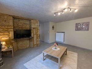 Una sala de estar con una mesa y un televisor. en Charmante maison de campagne avec terrasse et jardin - 2 appartements rénovés - FR-1-585-133, en Han-lès-Juvigny