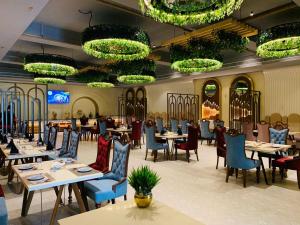 a dining room with tables and chairs and chandeliers at Hotel Miracle Resort in Phagwāra