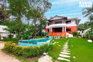 a house with a swimming pool in front of it at StayVista at Casa Chalora with Pool, BBQ, Games Room in Candolim