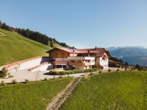 a house on top of a hill in a field at ALMRESIDENZ UNTERRAIN - with FREE SKI BUS SHUTTLE in Valdaora
