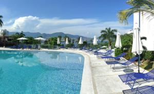a swimming pool with blue chairs and umbrellas at Hermoso Depto en Condominio Astoria in Acapulco